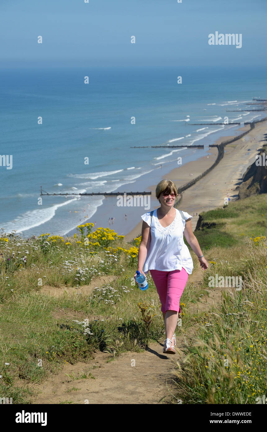 Woman walking the North Norfolk coastal cliff top path in summer, Beeston Bump, North Norfolk, England Stock Photo