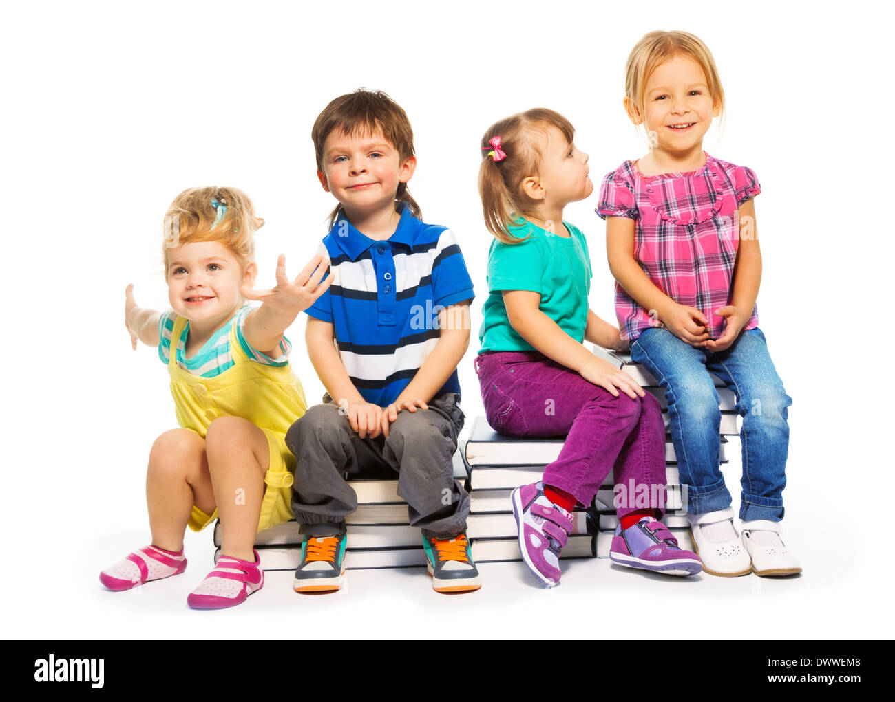 Four happy little kids sitting on the stairs of books Stock Photo