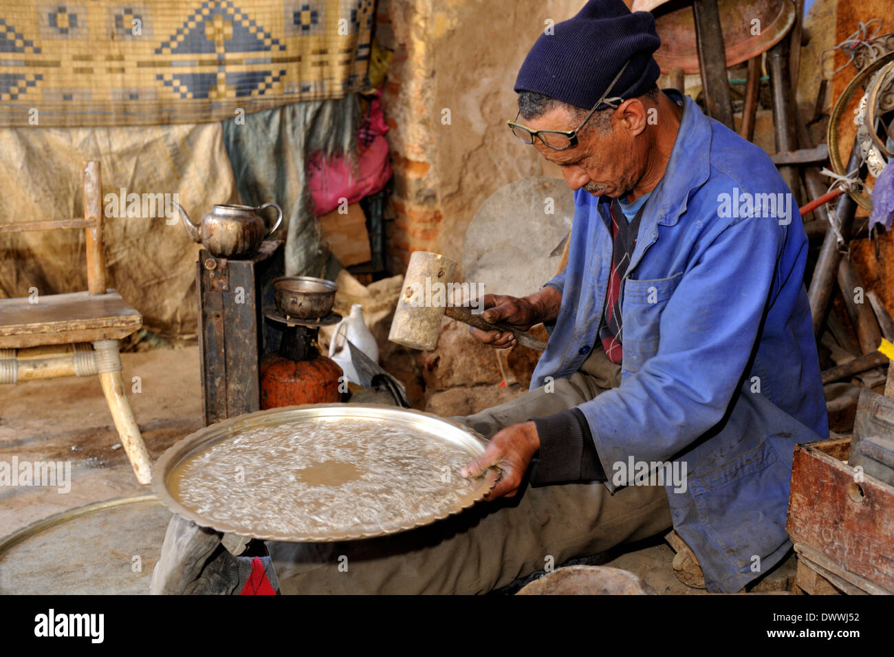 Metal smith in small workshop off one of the souks near Place Jemaa El Fna making serving tray Marrakech, Morocco, North Africa Stock Photo