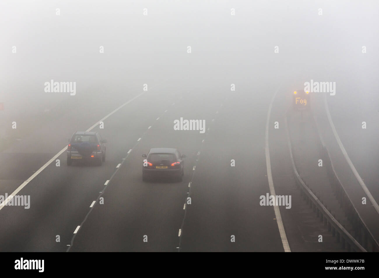 UK motorway with fog warning sign in fog or foggy conditions Stock