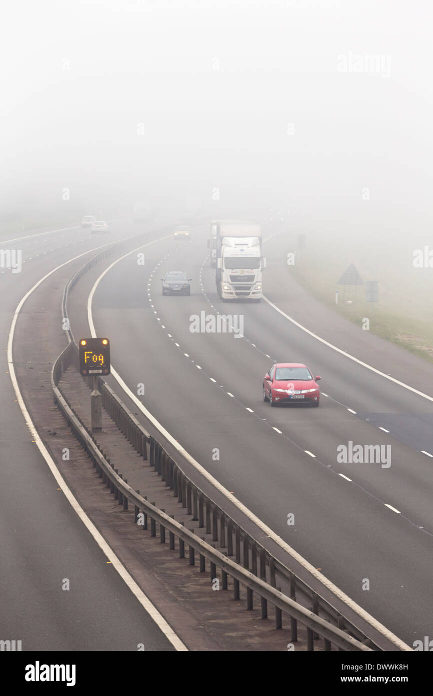 UK motorway with fog warning sign in fog or foggy conditions Stock