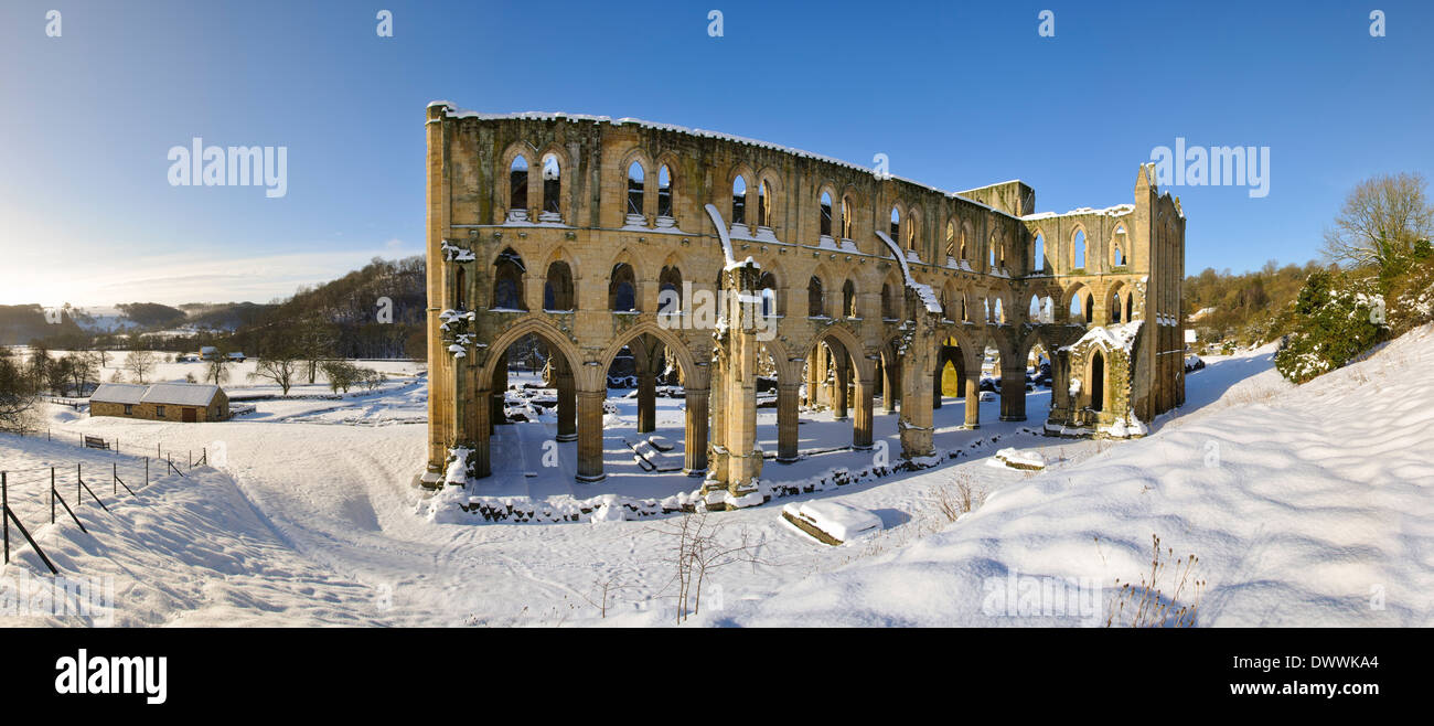 The ruins of Rievaulx Abbey under a heavy covering of snow on a bright winter's morning in the North York Moors National Park. Stock Photo
