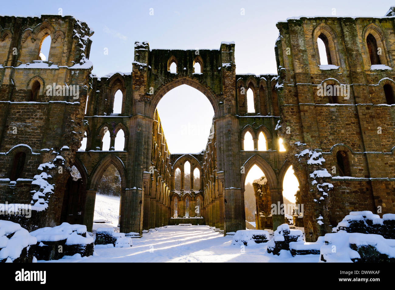 Sunlight shining through the arched windows in the ruins of Rievaulx Abbey under a  covering of snow on a bright winter's day Stock Photo