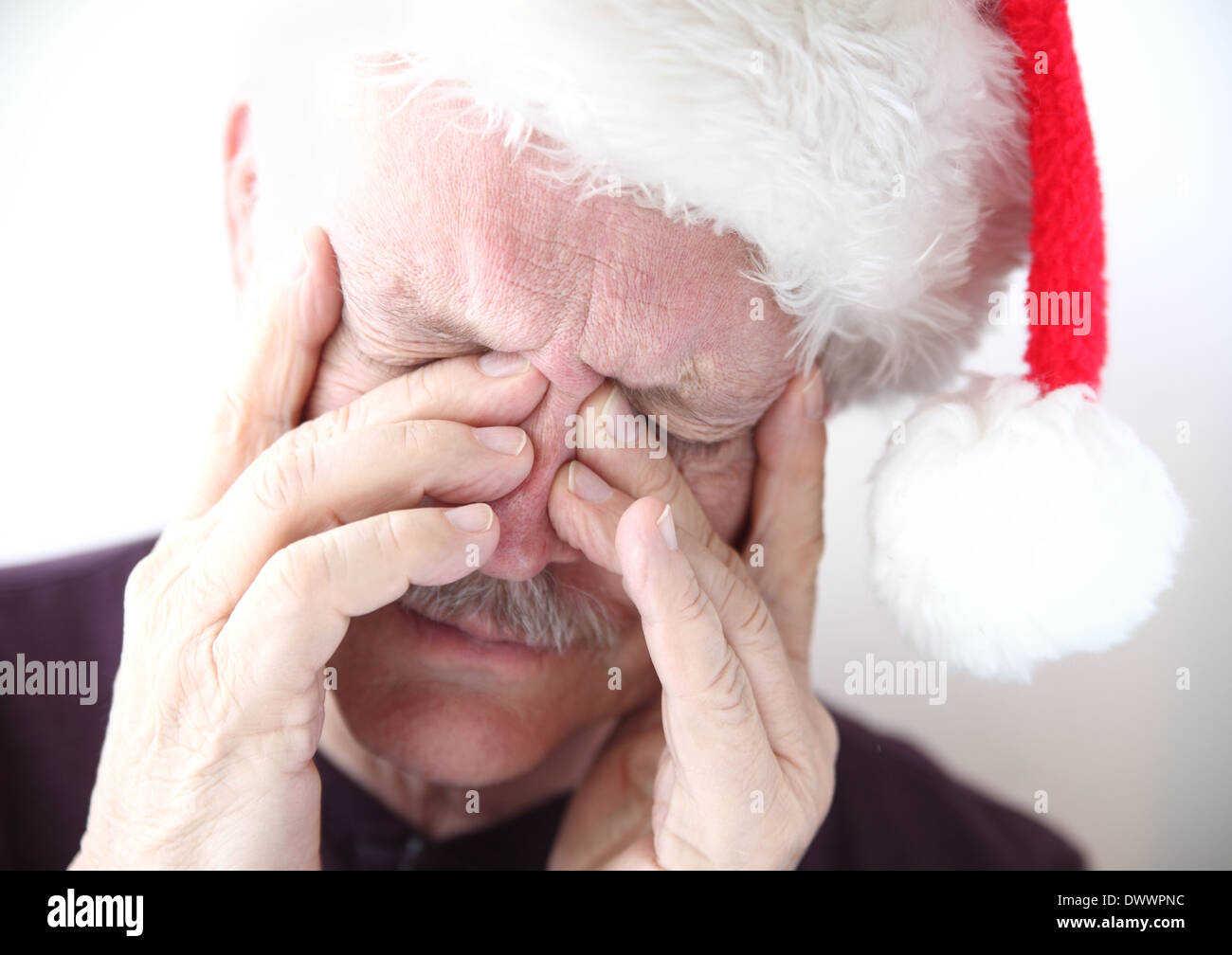 senior man wearing holiday hat has pain in his sinus area Stock Photo