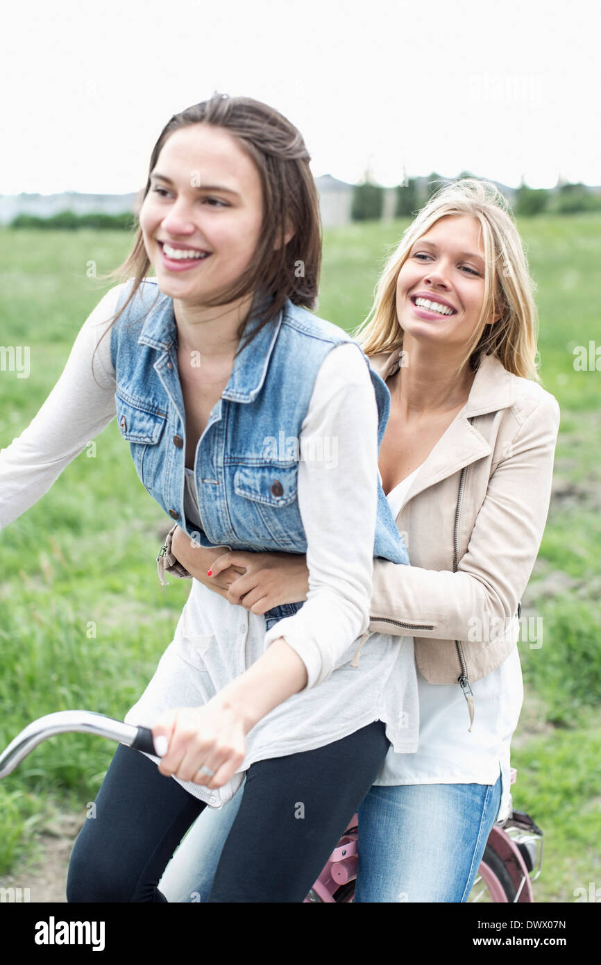 Happy female friends enjoying bicycle ride on country road Stock Photo ...