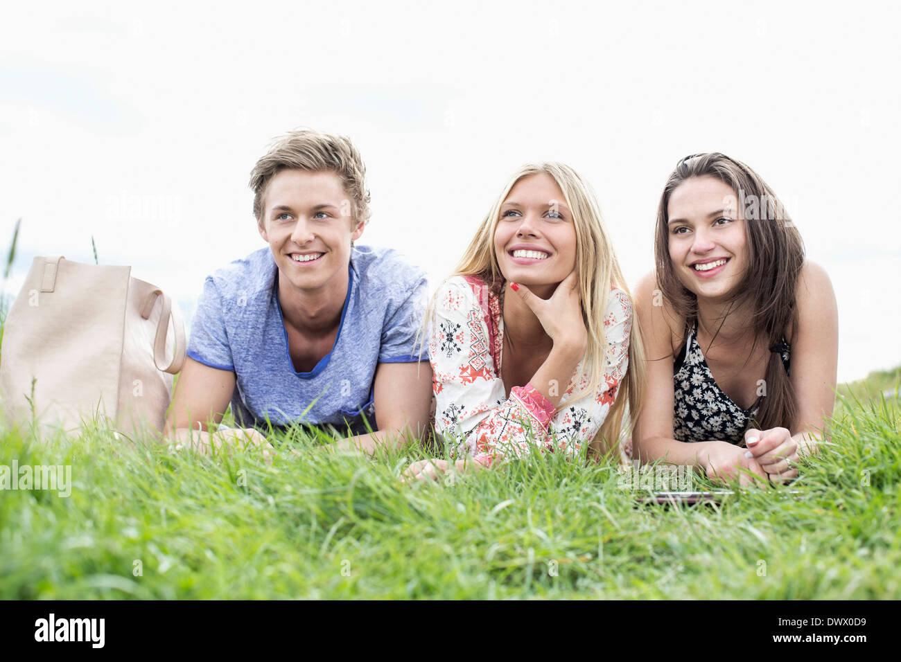 Thoughtful young friends looking away while lying on field Stock Photo