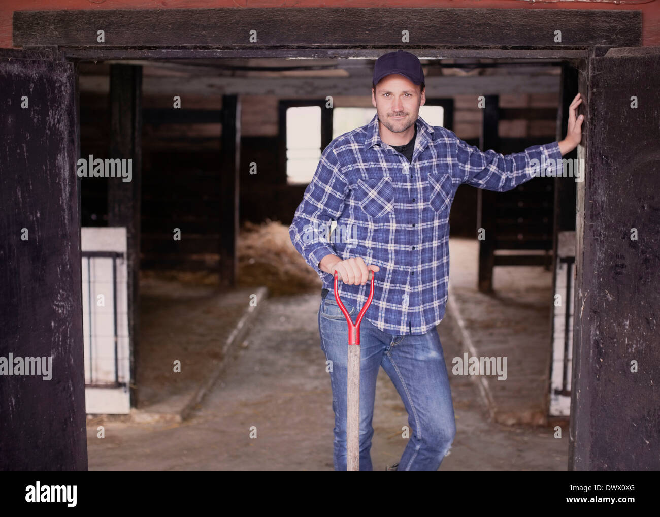 Portrait of confident farmer with pitchfork standing at the entrance of barn Stock Photo