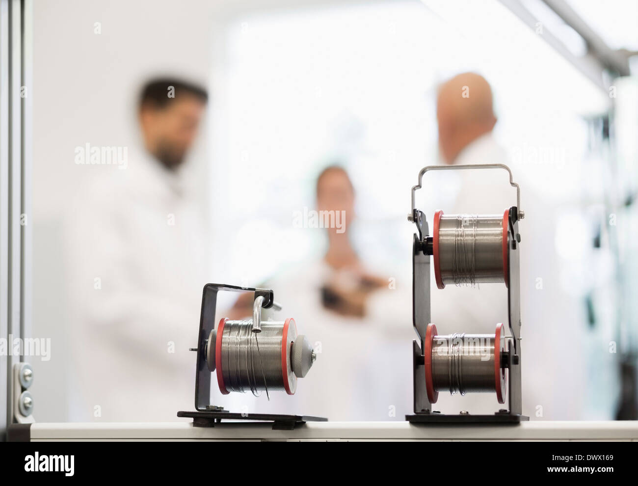 Spools of wire with engineers in background at machine industry Stock Photo