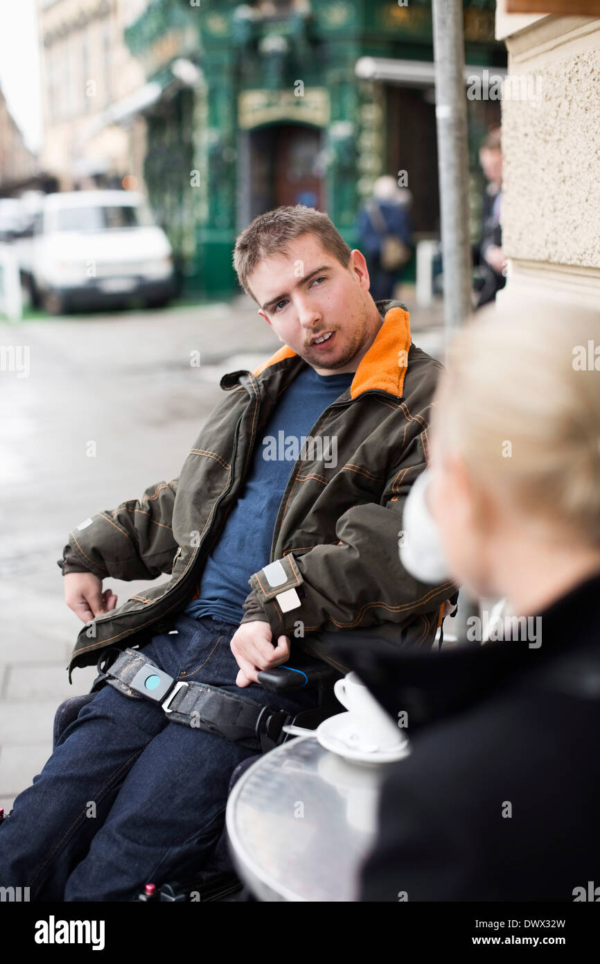 disabled-man-with-female-caretaker-at-sidewalk-cafe-DWX32W.jpg