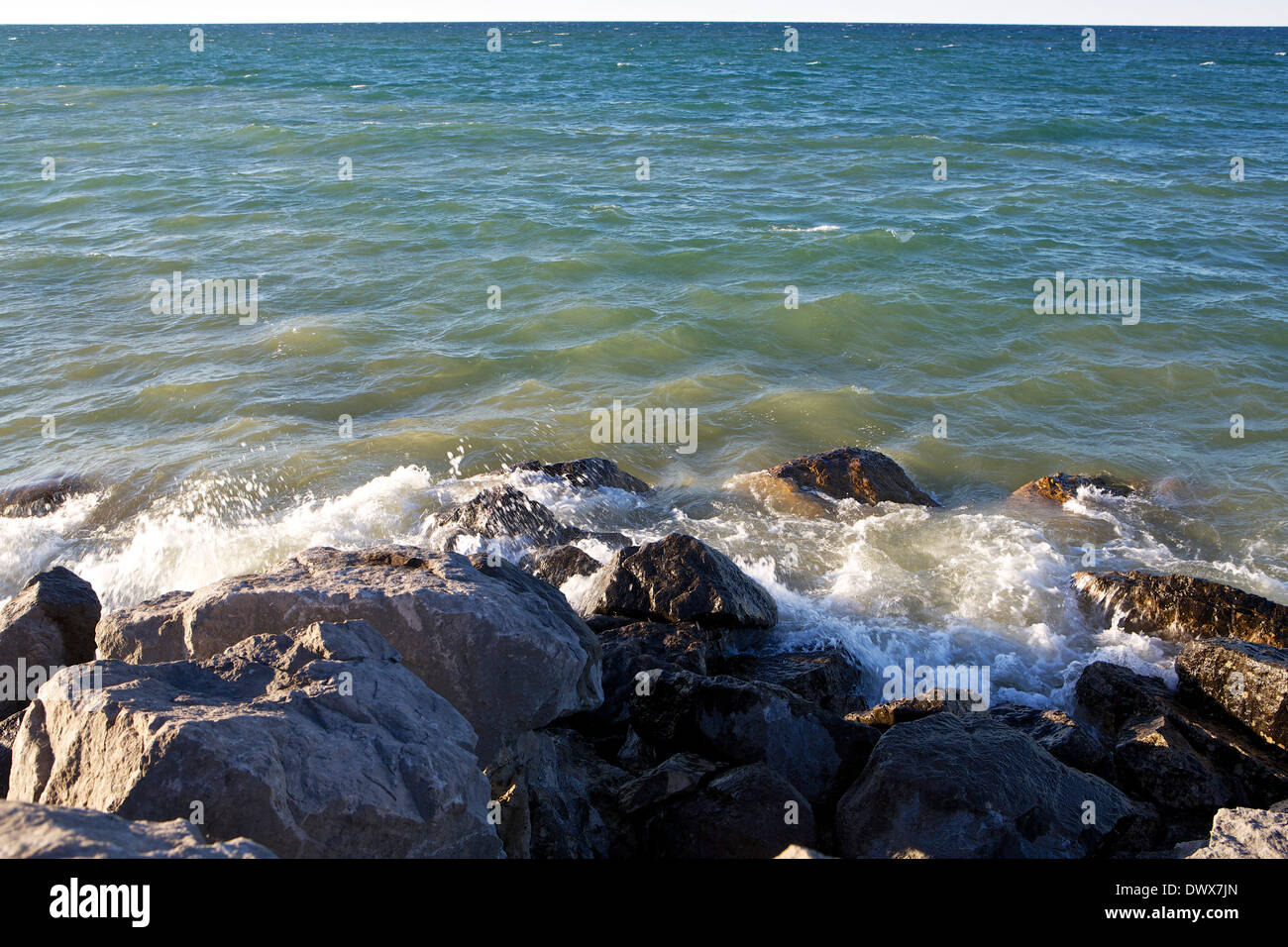 Lake Huron waves splashing up on rocks in Rogers City, Michigan Stock Photo