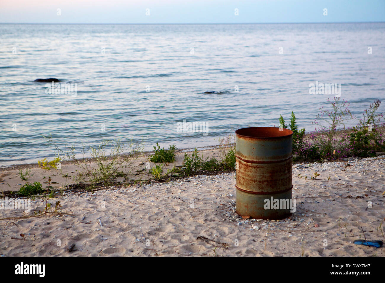 Trash barrel sitting on the beach on the shore of Lake Huron at twilight Stock Photo