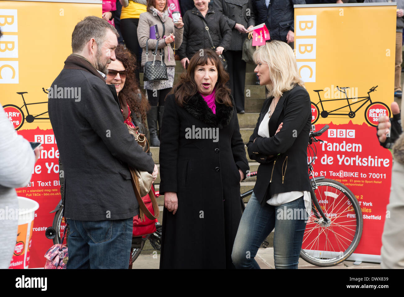 Before the start of Look North's Harry & Amy's Tandem Tour de Yorkshire in aid of Sport Relief. Kay Mellor & Linda Barker chatting, while crowd of supporters stands behind - Leeds Town Hall, West Yorkshire, England, UK. Stock Photo