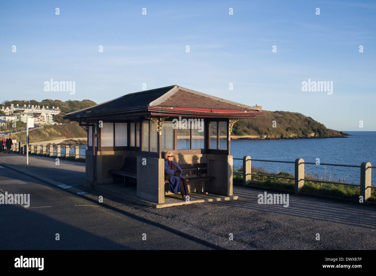 A pensioner sits in the early evening sun on Cliff Road in Falmouth