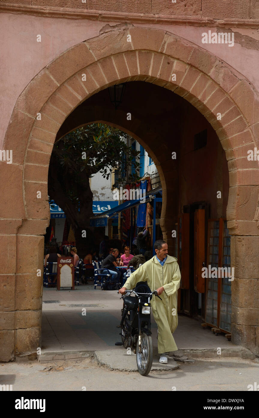 Traditionally dressed man walking with his motor bike. Essaouira. Morocco Stock Photo