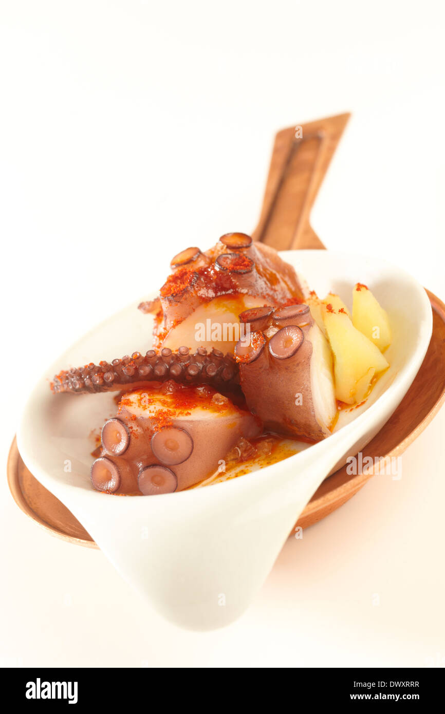 Typical 'Pulpo a la gallega' spansih tapa, made of boiled octopus, potato and paprika with olive oil, on a white background. Stock Photo