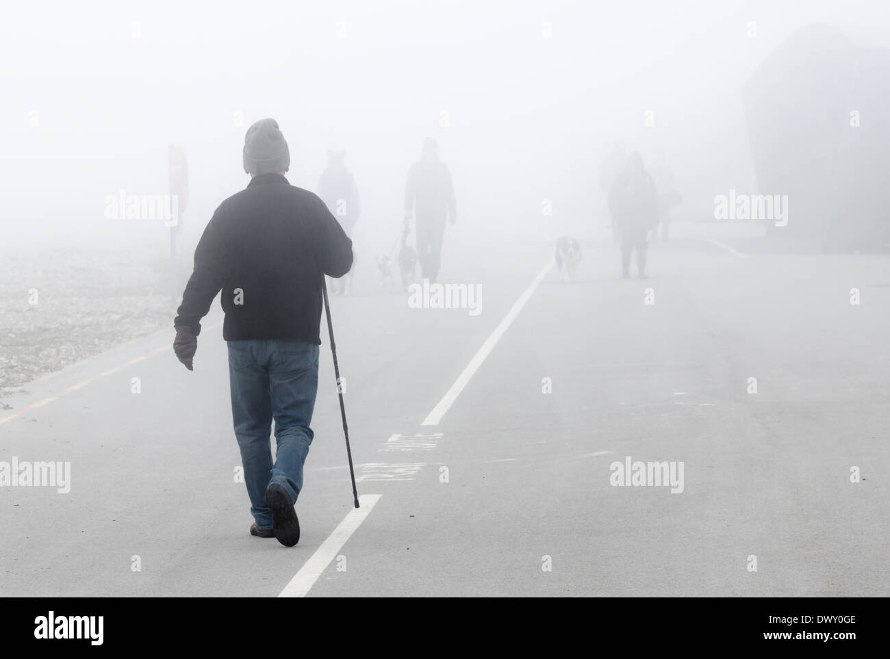 People walking along a promenade in the fog. Stock Photo