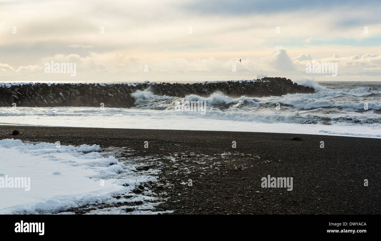 Strong Atlantic Ocean waves crash on a black rock jetty at Vík í Mýrdal in winter on the South coast of Iceland Stock Photo