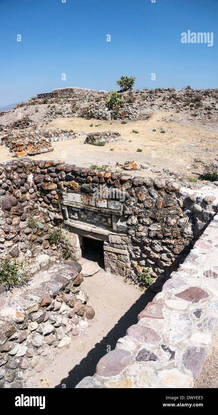 sunken entrance to tomb with stone mosaic frieze above lintel on hill below Patio 1 in ruins of ancient city of Yagul Oaxaca Stock Photo