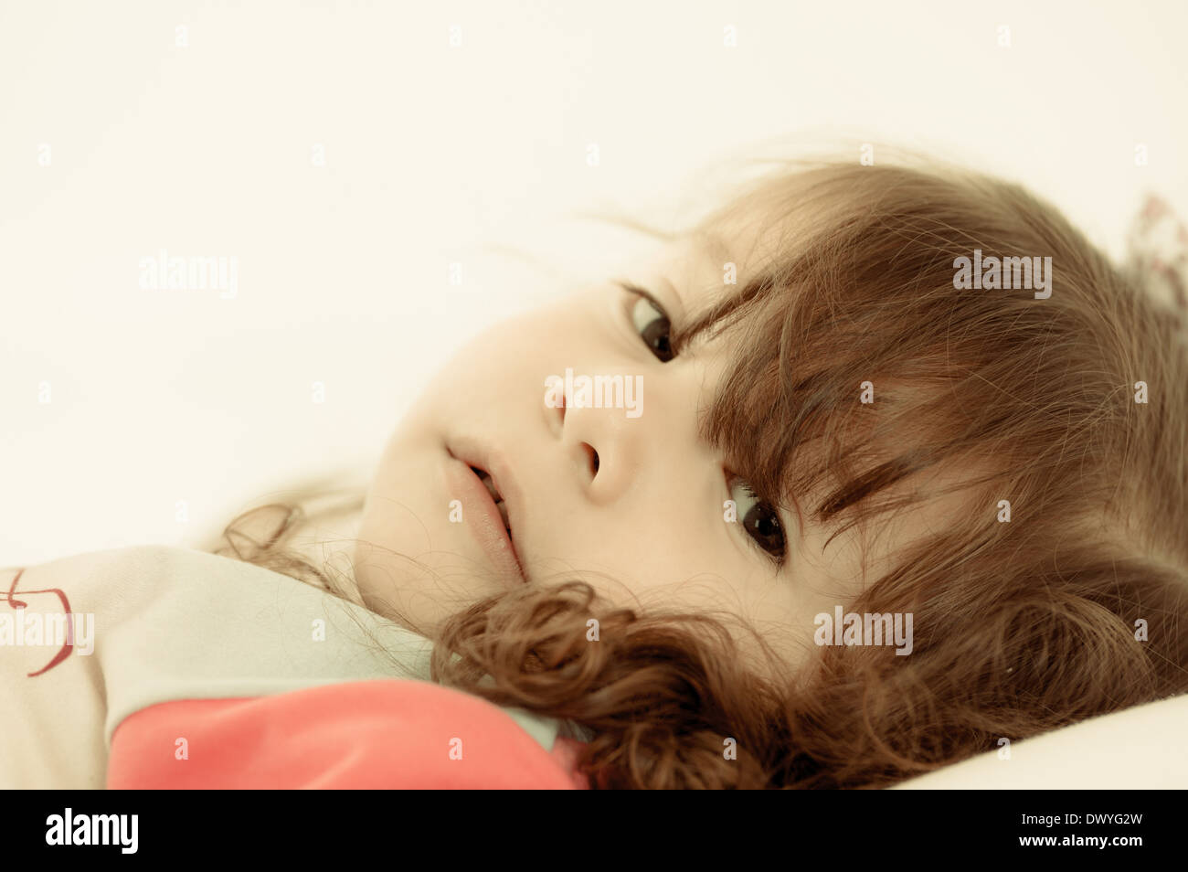 Sad little girl lying in bed colortoned Stock Photo