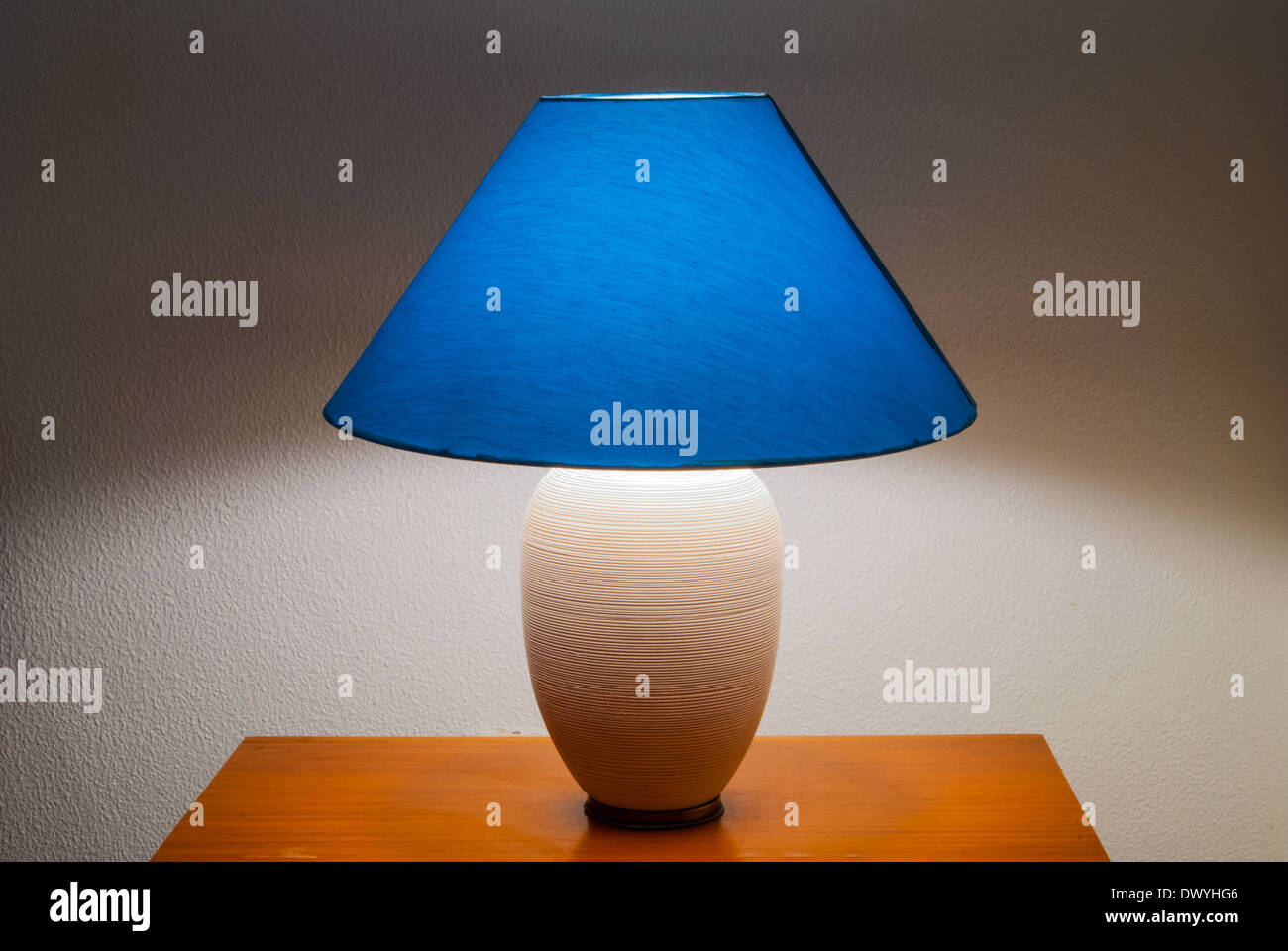 Lamp on a nightstand with a blue glow on a textured walldiffused