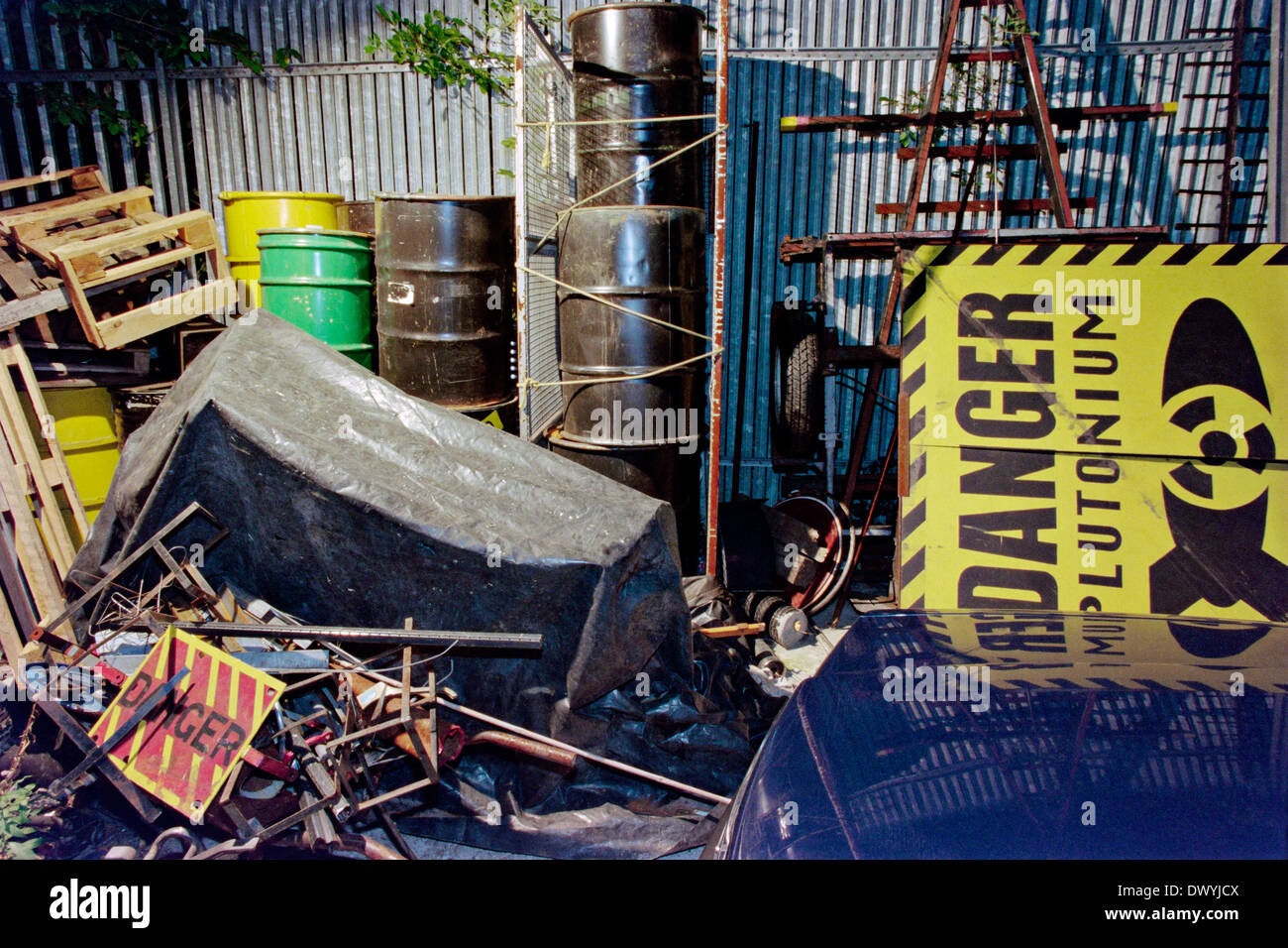 A ' Danger Plutonium' warning sign and old oil drums in a backyard. Stock Photo