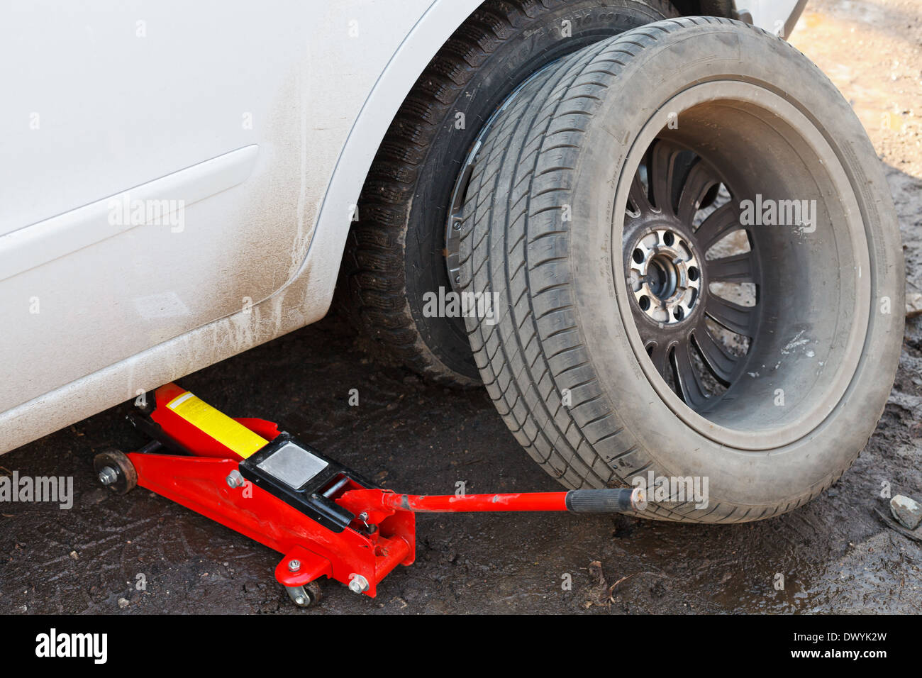 seasonal replacement of tires with jack outdoors lifting car by