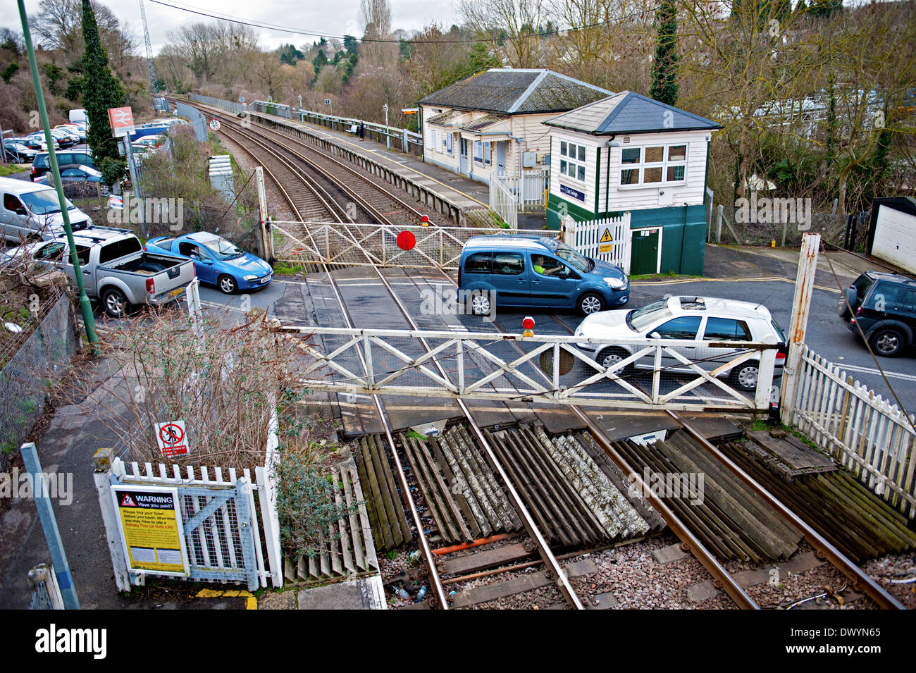 Road traffic crossing the railway line at East Farleigh railway station with traditional gates and signalbox Stock Photo