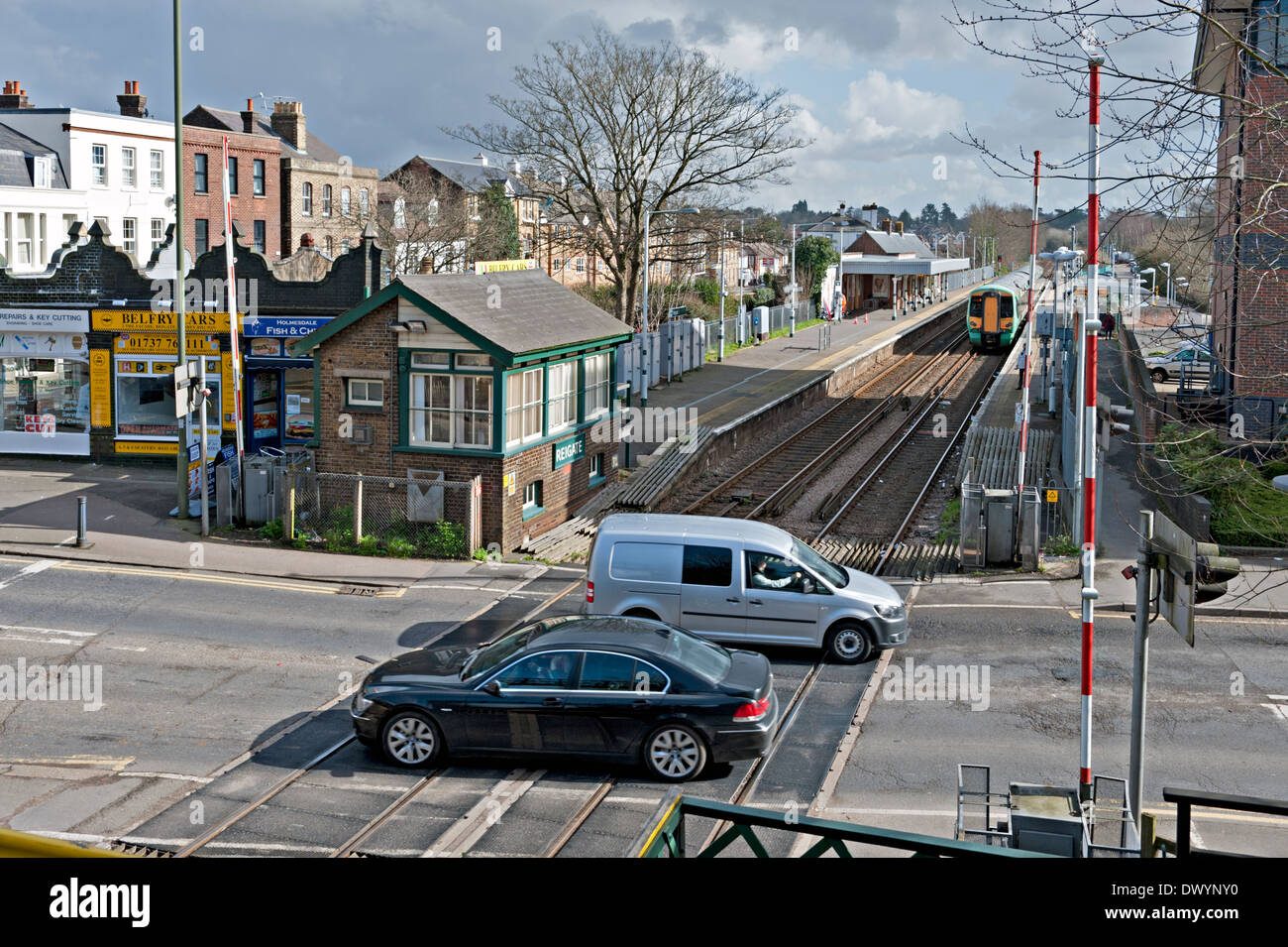 Vehicles crossing the railway line at Reigate signalbox and station in