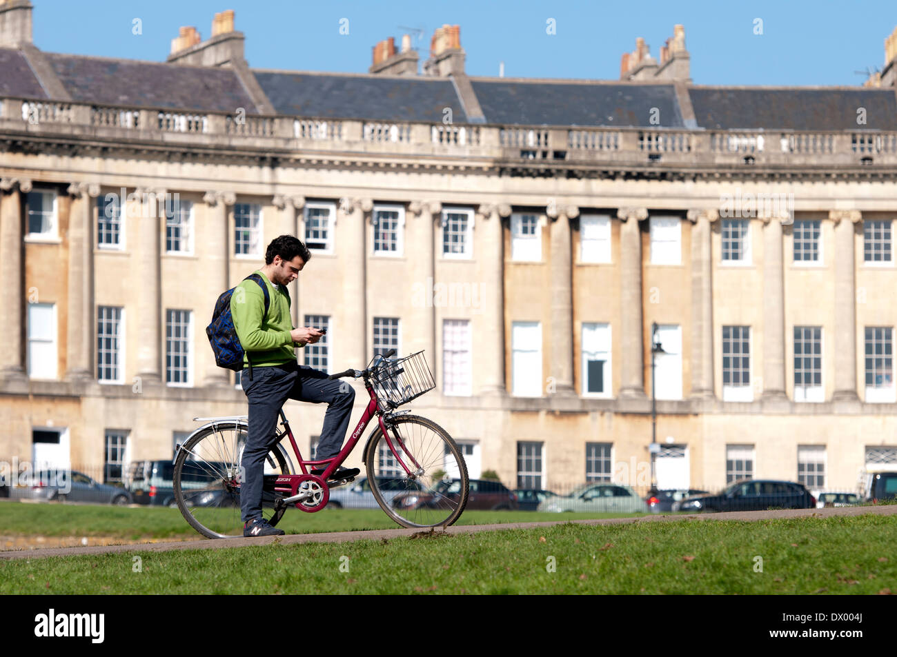 Cyclist sending text message, Royal Crescent, Bath, Somerset, England, UK Stock Photo