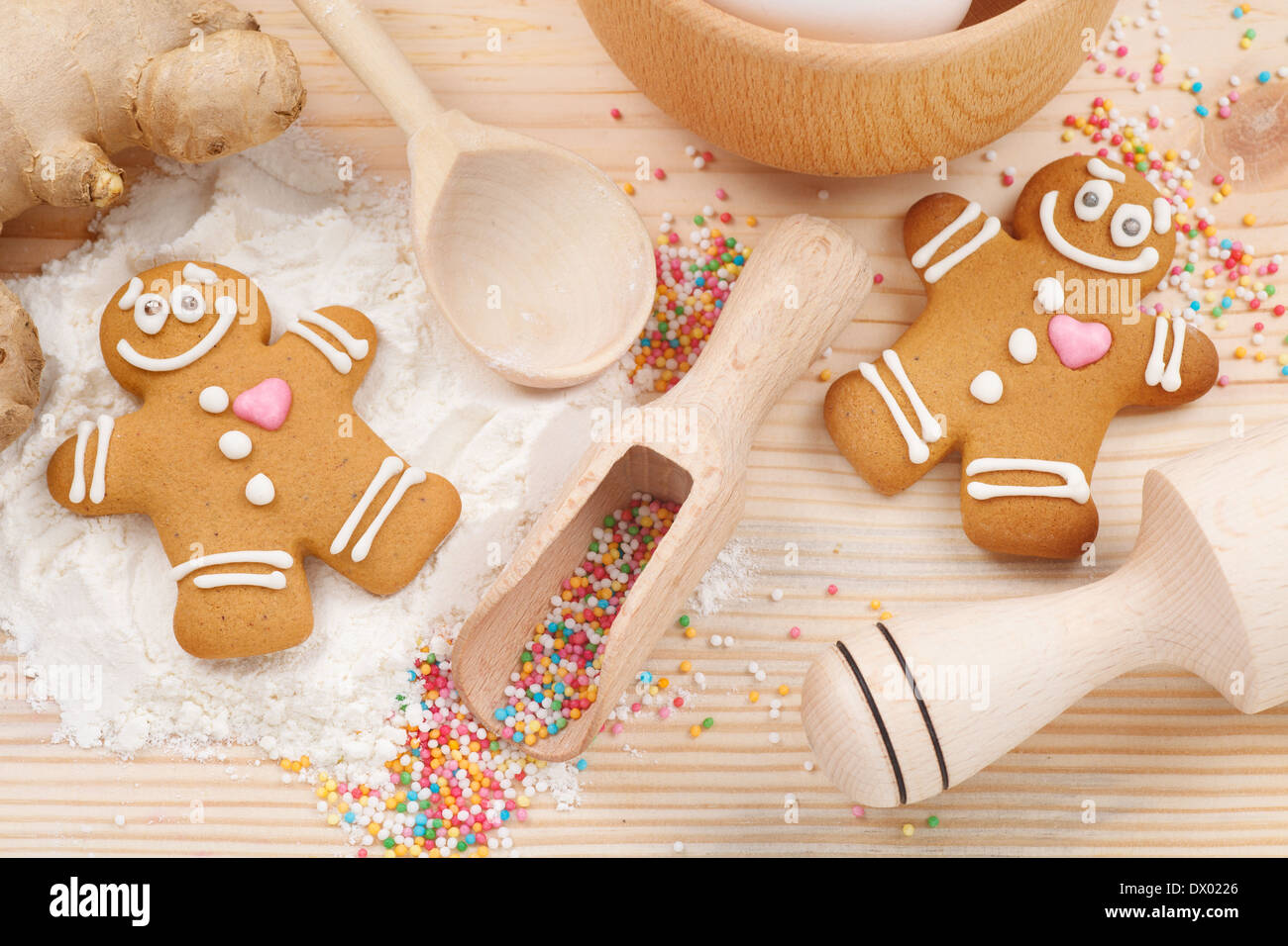 funny gingerbread men, flour, rolling pin, spoon and ginger on kitchen table Stock Photo