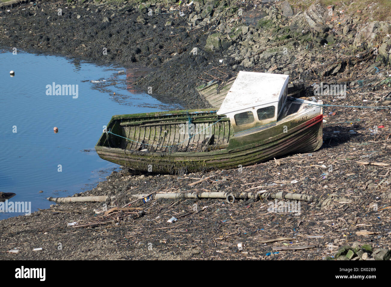 A derelict clinker built wooden fishing boat abandoned and flooded at every tide Stock Photo