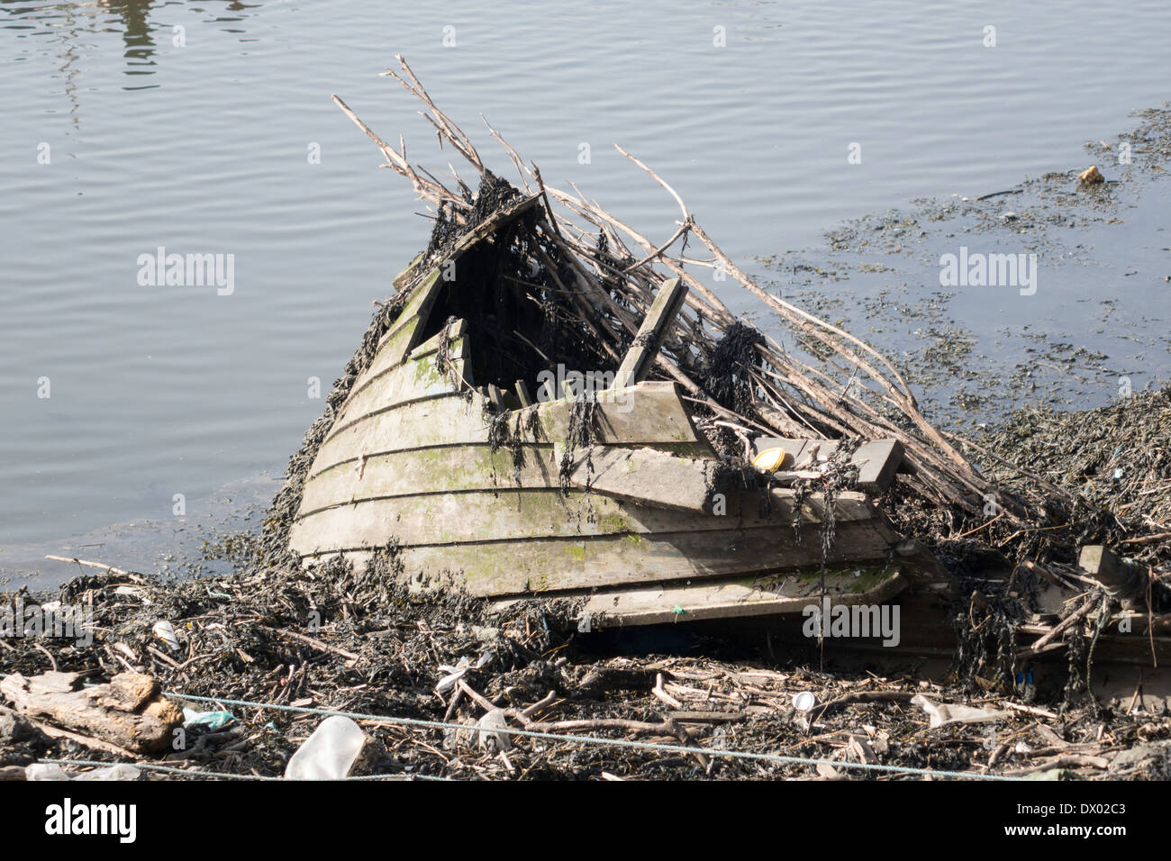 Remains of bow section of derelict clinker built wooden fishing boat abandoned and flooded at every tide Stock Photo