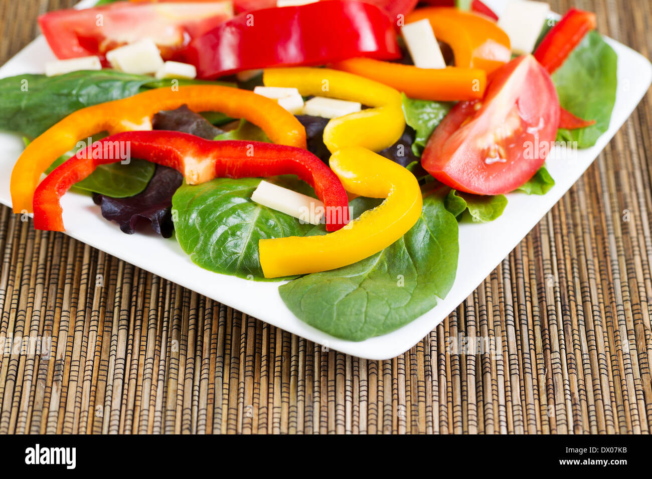 Horizontal photo of a fresh salad on a white plate with bamboo mat underneath Stock Photo