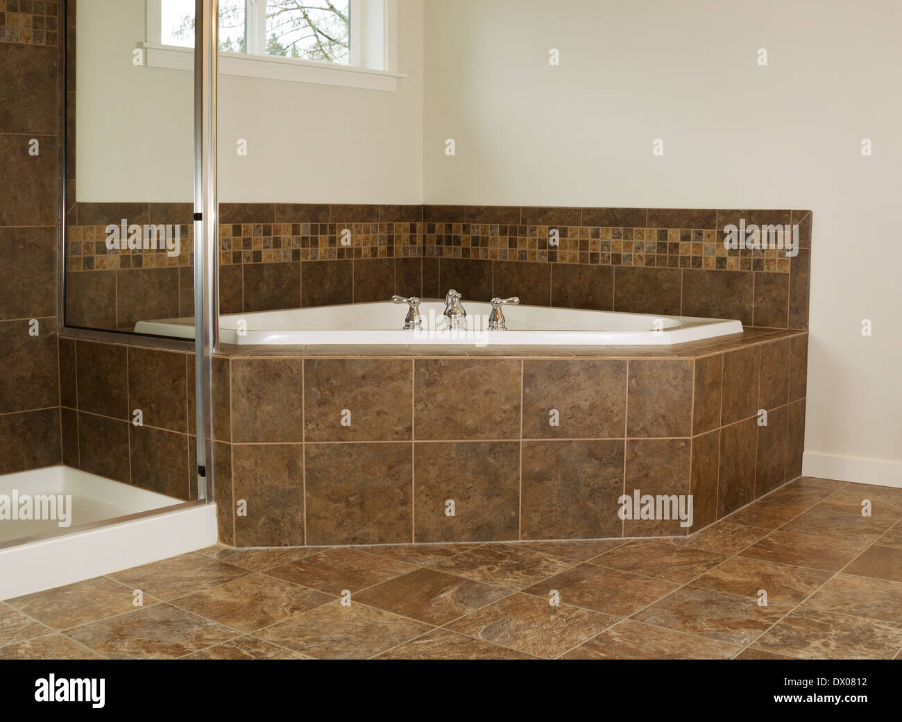 Horizontal photo of soaking tub in master bathroom with partial shower and windows Stock Photo