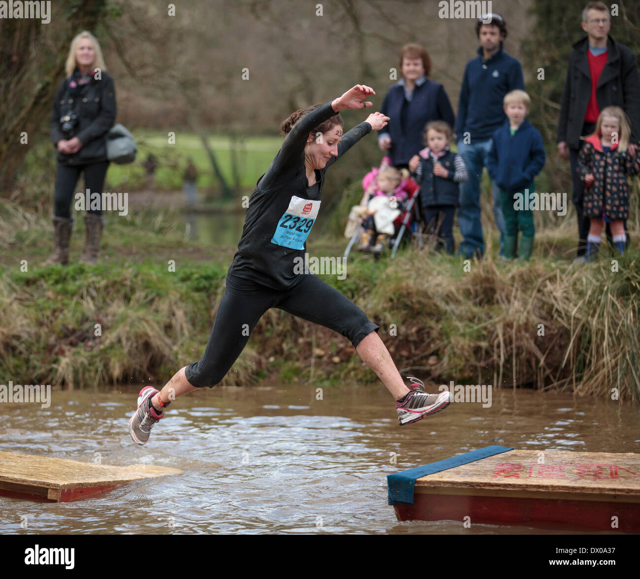 Exeter, Devon. March 15th 2014. A woman leaps across floating stepping stones on an obstacle course at Escot Park .Over 3,500 entrants entered the event which promotes fitness and team spirit. Credit:  Nick Cable/Alamy Live News Stock Photo
