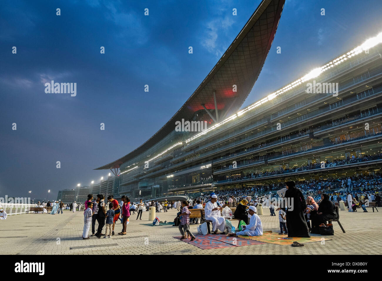 Spectators and grandstand at horse racing meeting at Al Meydan racecourse at night in Dubai United Arab Emirates Stock Photo