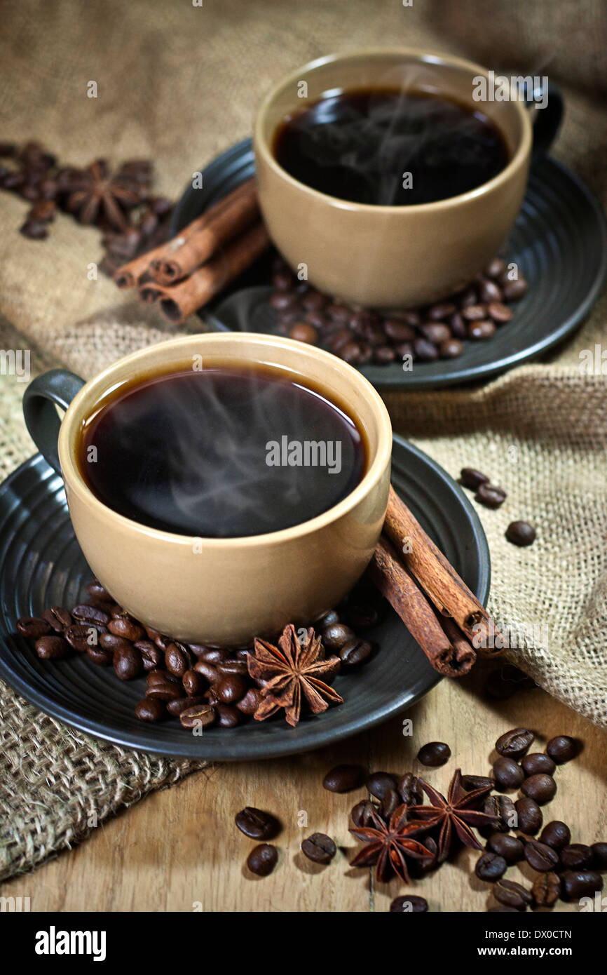Two ceramic cups of coffee with cinamon and star anise on old coffee ...