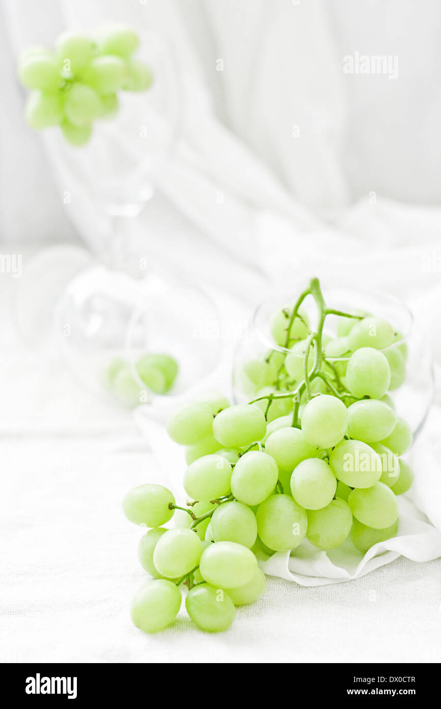 Bunch of white grapes in thin glass goblet on white background. High key. Stock Photo