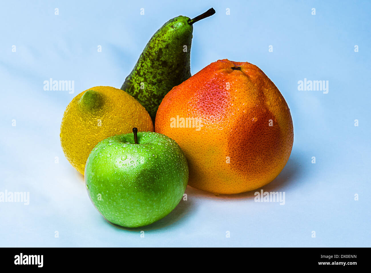 Fruits. Closeup view of colorful fruits: orange grapefruit, green apple, yellow lemon and green and pear against blue background Stock Photo