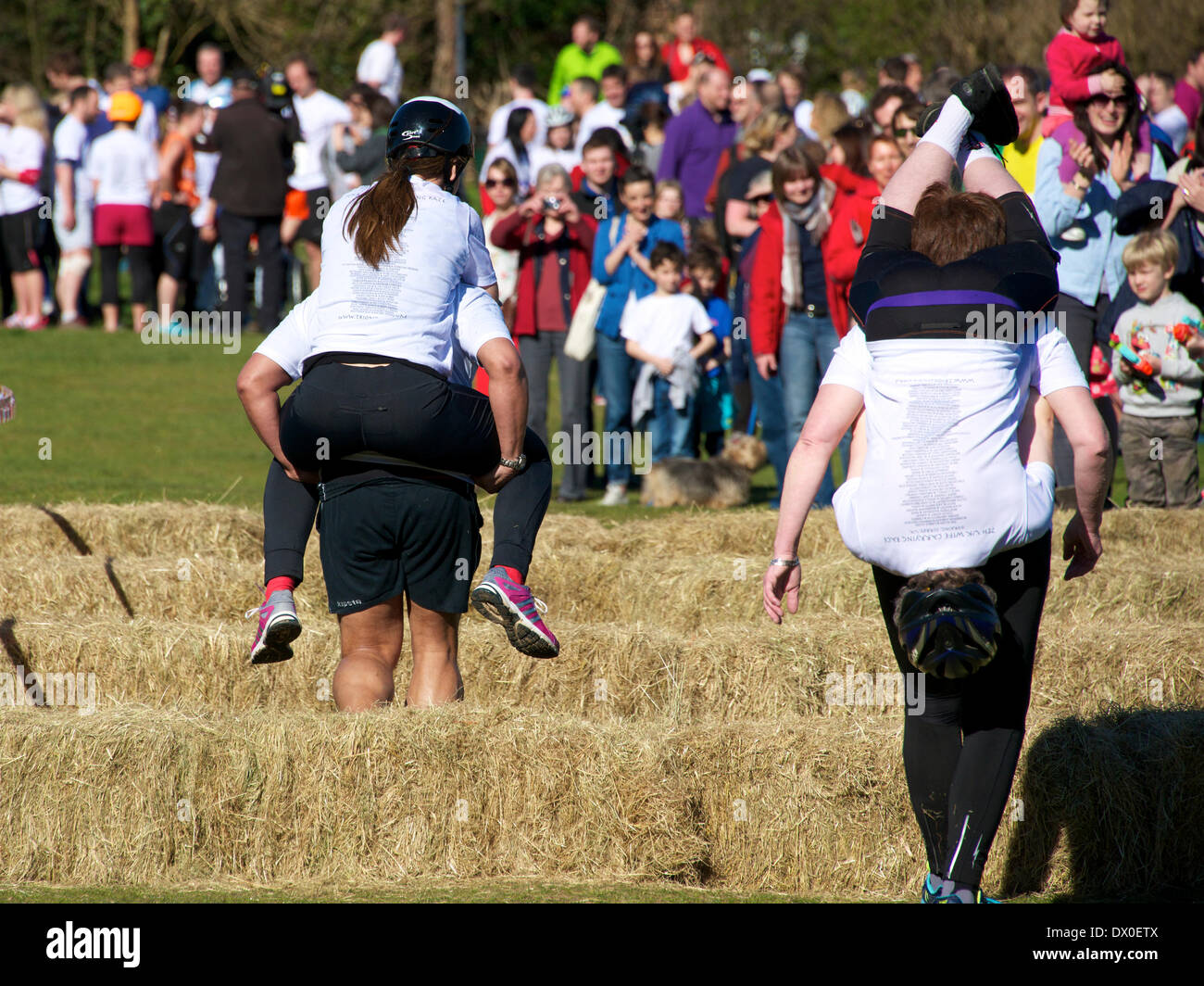 Dorking, Surrey. Sunday 16th March 2014. The 7th UK Wife Carrying Race takes place at The Nower Dorking. Image shows a very tired Ivan Gutierrez carrying 77kg Lisa Gregory on the left and Belgian competitors Myrienne Amrani carrying 72kg Herwig Delvaux on the right Credit:  Photo by Lindsay Constable/  Alamy Live News Stock Photo