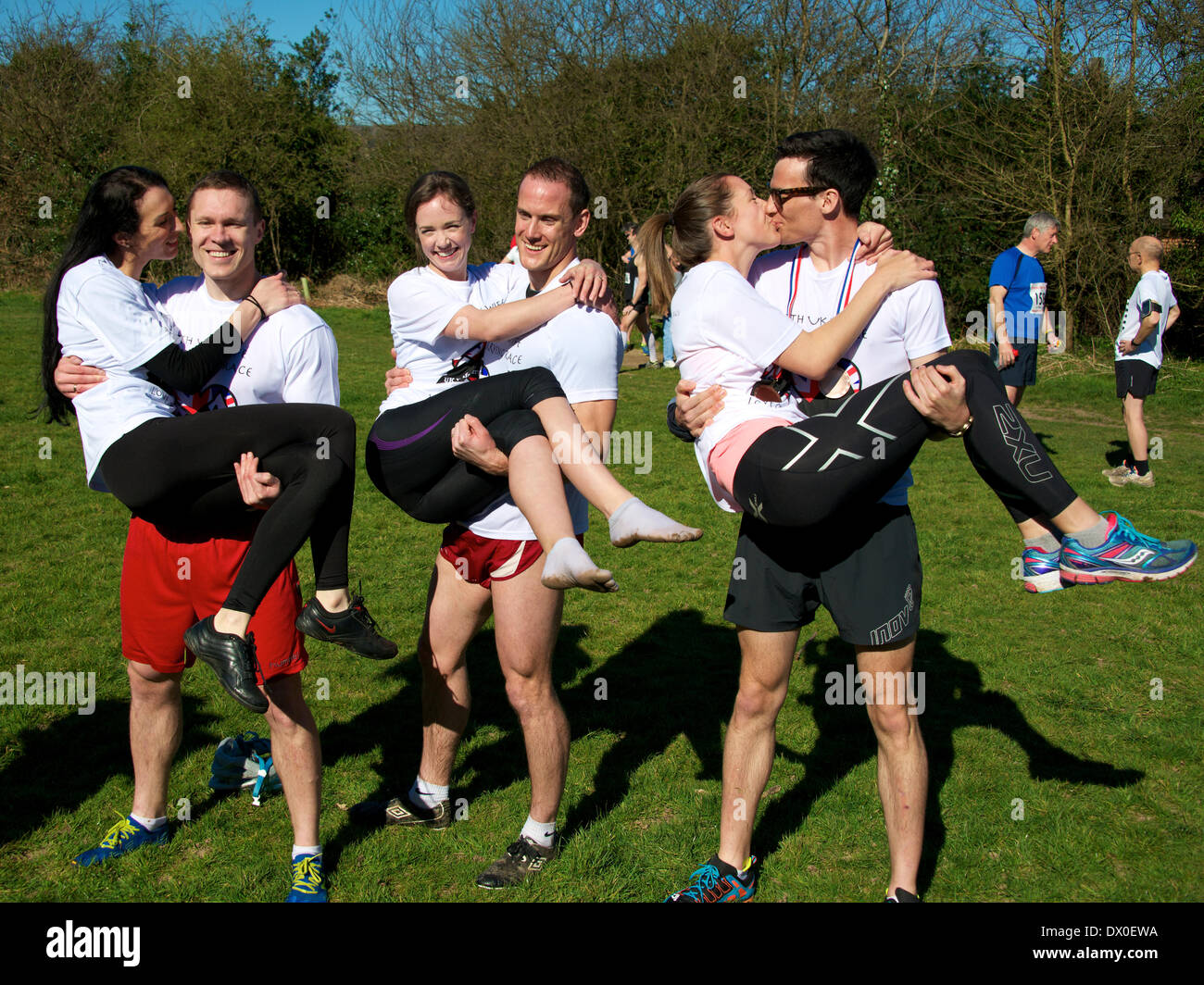 Dorking, Surrey. Sunday 16th March 2014. The 7th UK Wife Carrying Race takes place at The Nower Dorking. Image shows the three finalists with Rich Blake Smith and 55kg Anna in the middle, in second place on the left is Vytautas Kirkliauskas with 52kg wife Neringa Kirkliauskiene and third place on the right, Benjamin Hall and 61kg Gemma Taylor Credit:  Photo by Lindsay Constable/  Alamy Live News Stock Photo