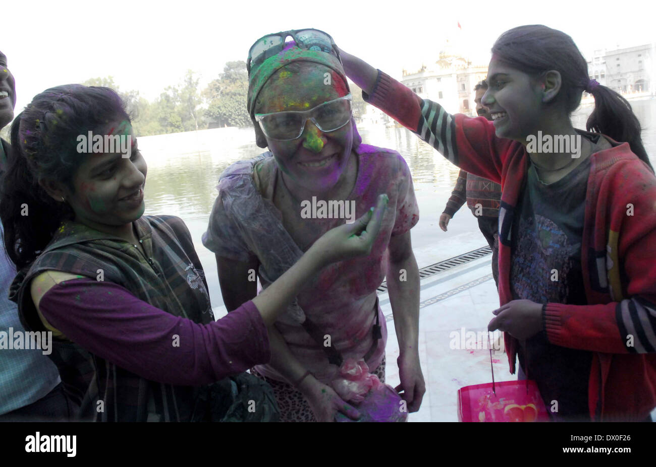 Amritsar, India. 16th March 2014. Tourists play with coloured powder as celebrating Holi at Durgiana Temple in Amritsar on Sunday. Holi, the Hindu festival of colors that also marks the advent of spring, is being celebrated across the country Monday. Credit:  PACIFIC PRESS/Alamy Live News Stock Photo