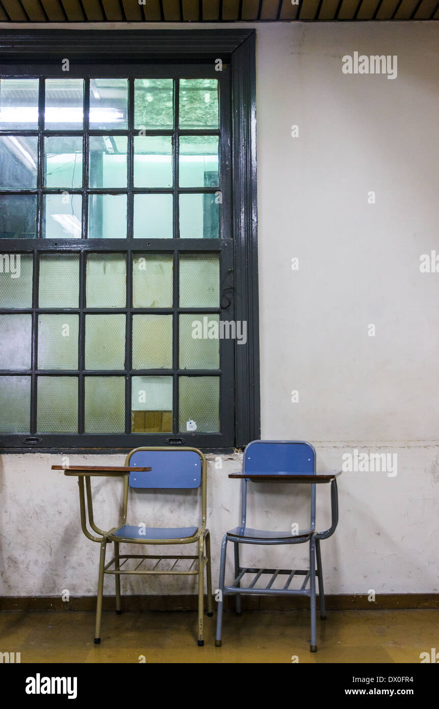 Pair of old chairs and desks in an old worn down classroom Stock Photo