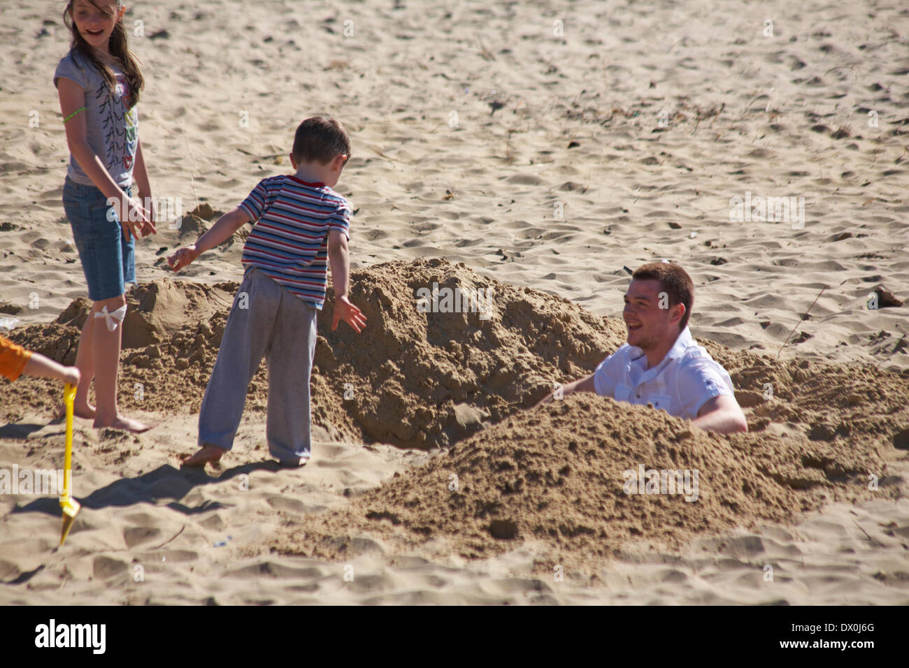 Boy digging big hole in sand at the beach hires stock photography and