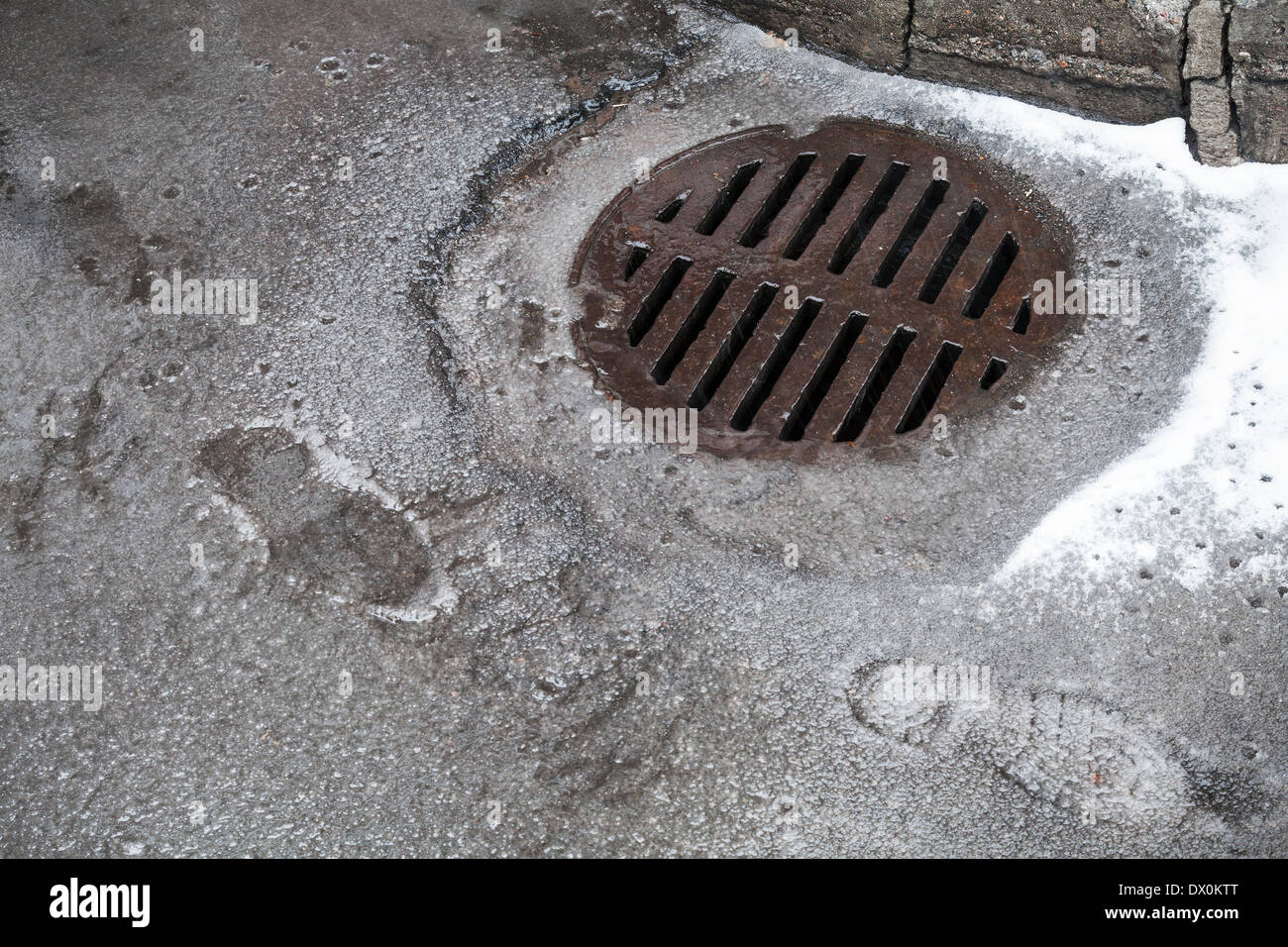 Sewer manhole on the urban asphalt road with wet snow Stock Photo