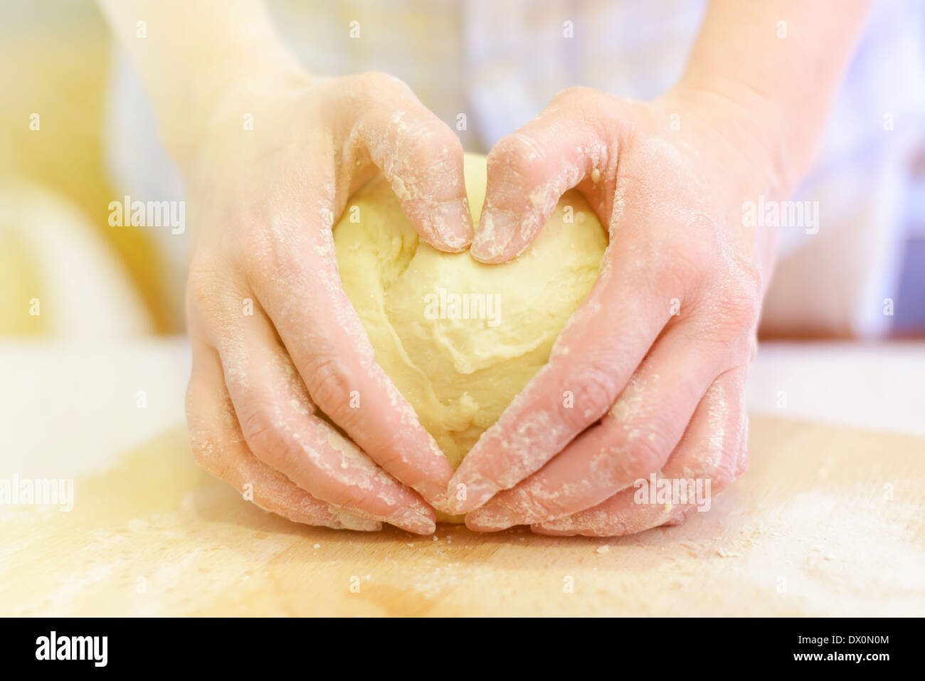 Cooking woman hands kneading dough, closeup shot, fingers forms heart