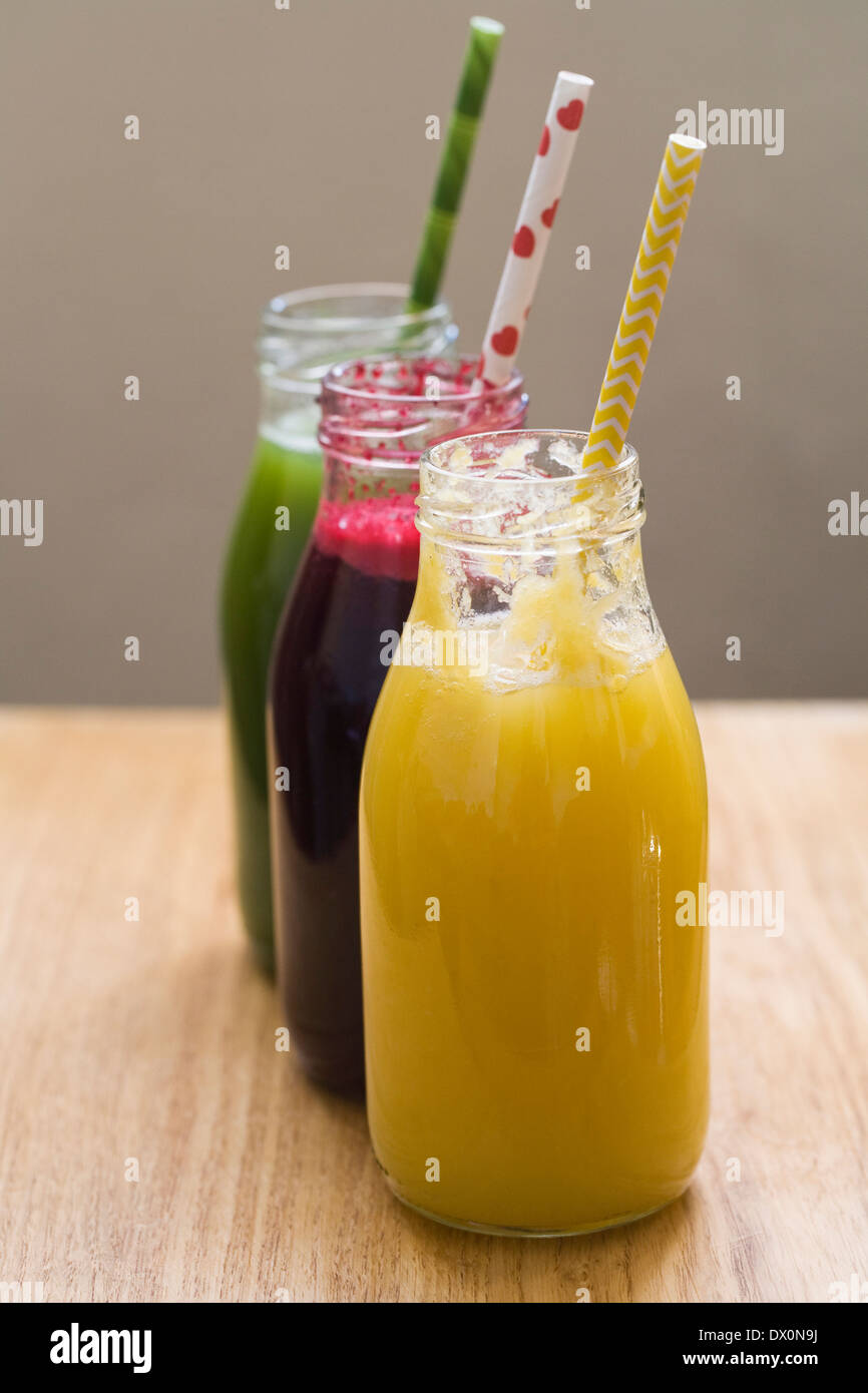 Three freshly squeezed juices in glass bottles. Stock Photo
