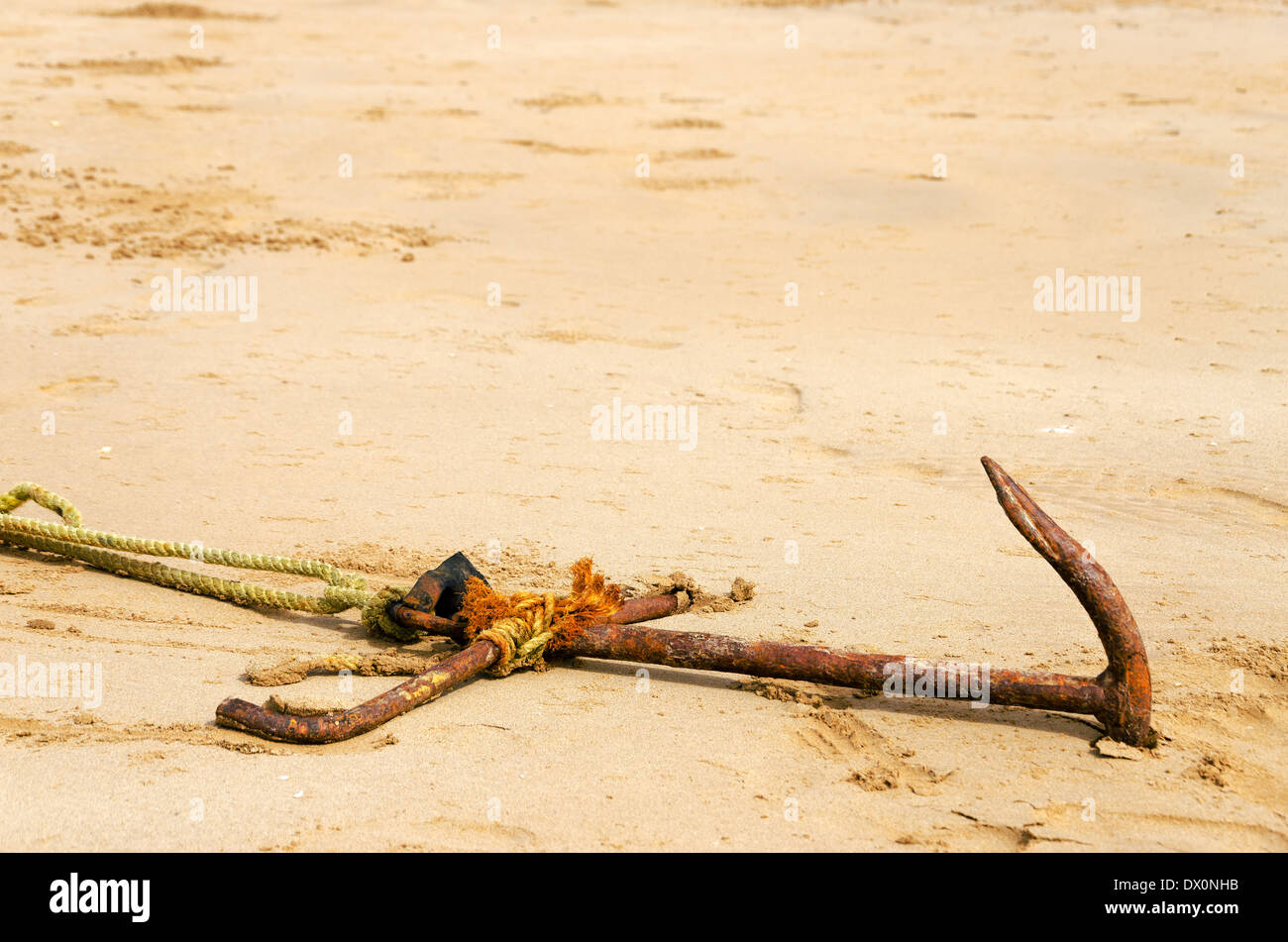 Old rusted anchor buried in sand Stock Photo