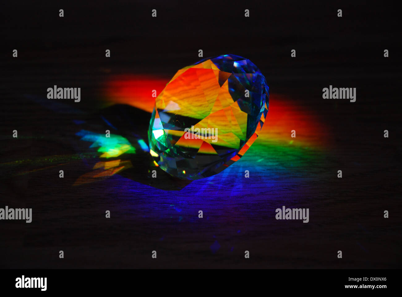 Prism casting rainbows against dark background Stock Photo