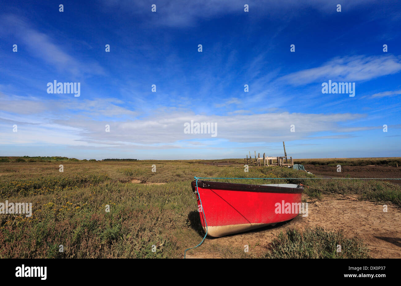 Red boat on the marshes at Thornham harbour on the North Norfok coast. Stock Photo
